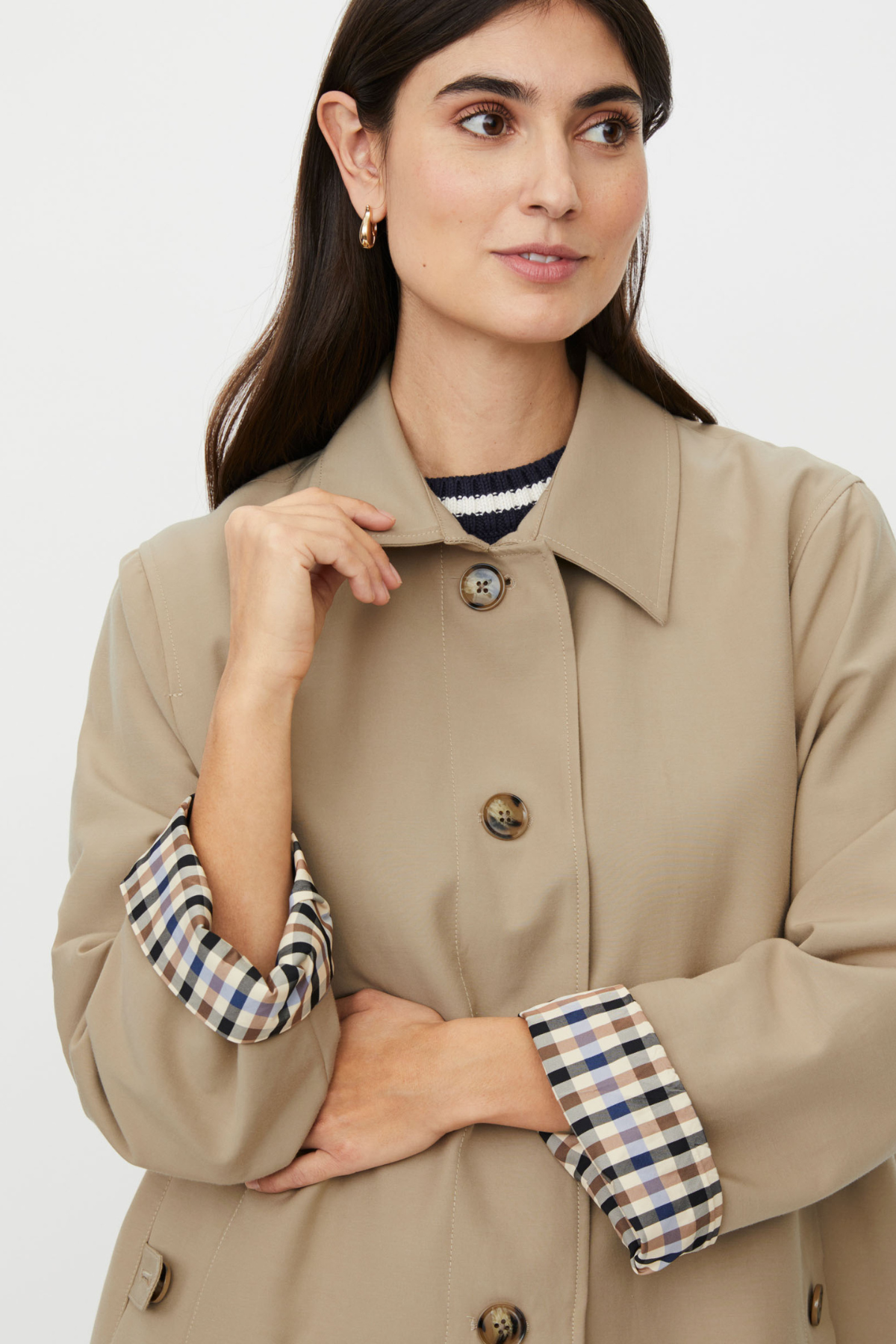Mid-length lightweight beige trench coat with brown and blue checked lining. Tortoiseshell buttons, pocket detailing and classic collar make this a staple.