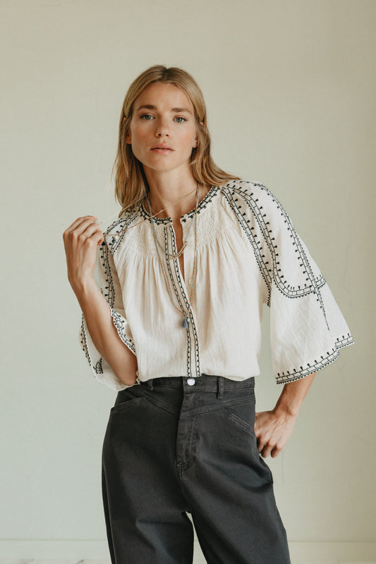 Cream bell-sleeve lightweight textured blouse with black embroidery border detail. 