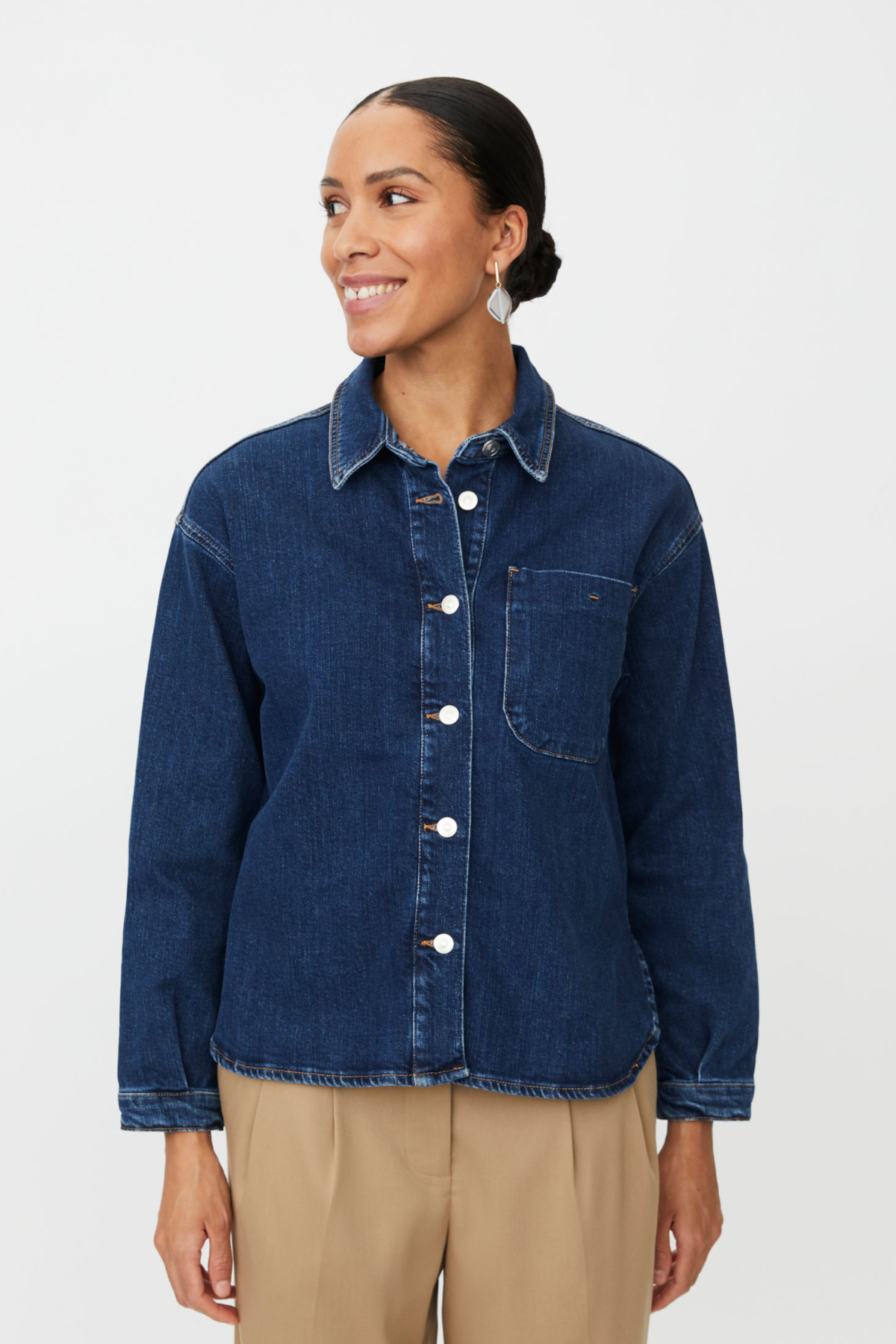 Blue denim jacket with curved hem, classic collar, button-down front and pocket detail.