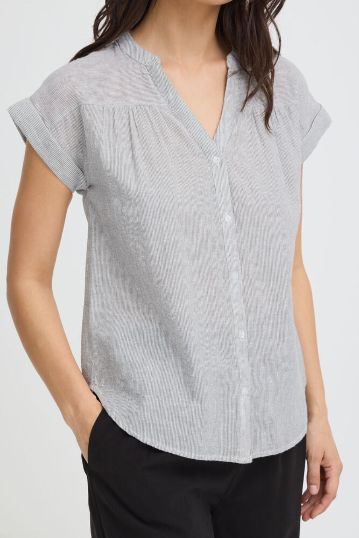 Woman wearing a light gray short-sleeve blouse on a white background
